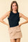 woman wearing a black sleeveless top with ruffle details and a beige mini skirt with pockets