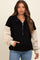 woman wearing a black and cream oversized maternity pullover sweatshirt with a half zip and pocket