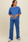 woman wearing a blue maternity top and matching pants, holding her baby bump