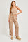 woman wearing a beige cropped tank top and matching wide-leg cargo pants with side pockets and platform sandals