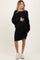 woman wearing a black cable knit maternity dress with long sleeves and holding her baby bump