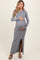 woman wearing a grey long sleeve maternity dress with a side slit and holding her baby bump