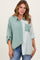 woman wearing a mint green and striped button-up shirt with a front pocket and rolled-up sleeves