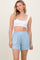 woman wearing a white crop top and light blue elastic waist shorts