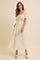 woman wearing an ivory maxi dress with floral detailing and flutter sleeves, standing against a neutral background