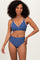 woman wearing a blue bikini with white trim and high-waisted bottoms, smiling at the camera