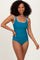 woman wearing a teal one-piece swimsuit with white scallop trim and a flattering fit