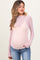 woman wearing a sheer pink maternity top with heart patterns and long sleeves, showing a baby bump