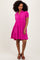 woman wearing a bright pink short sleeve tiered dress with a button-down collar and a flared silhouette