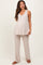 woman wearing a beige maternity top and matching pants, gently flowing with a visible baby bump