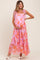 woman wearing a pink floral maternity maxi dress with tie straps and holding her baby bump
