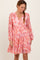woman wearing a pink floral long sleeve dress with a v-neck and ruffled skirt