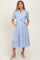 woman wearing a light blue striped maternity dress with short sleeves, button details, pockets, and a tie waist
