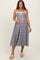 woman wearing a black and white gingham maternity dress with lace trim and holding her baby bump