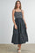 woman wearing a black and white striped spaghetti strap maxi dress with a tiered skirt