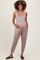 woman wearing a taupe maternity jumpsuit with a scoop neckline and pockets, gently cradling her baby bump