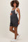woman wearing a dark gray striped maternity romper with pockets, gently cradling her baby bump