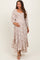 woman wearing a floral print maternity maxi dress with a smocked bodice and tiered hem, gently cradling her baby bump