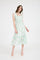 woman wearing a green and white floral midi dress with ruffled straps and a tiered skirt