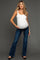 woman wearing a white maternity tank top and blue flared maternity jeans, showing her baby bump