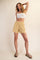 woman wearing a white crop top and yellow drawstring shorts, standing with one hand on her hip