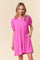 woman wearing a pink short sleeve polo style dress with a textured pattern and side pockets