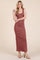 woman wearing a rose-colored sleeveless maxi dress standing with one hand on her hip and smiling