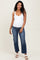 woman wearing a white maternity tank top and blue cropped jeans with a visible baby bump