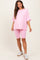 woman wearing a pink oversized t-shirt and matching bike shorts, showcasing a casual maternity outfit