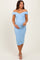 woman wearing a light blue off-shoulder maternity dress with a fitted silhouette and holding her baby bump