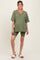 woman wearing an olive green oversized v-neck maternity tee and matching bike shorts, showing her baby bump