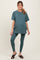 woman wearing a teal oversized maternity t-shirt and matching leggings, showcasing her baby bump