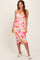woman wearing a vibrant floral midi dress with a wrap design and spaghetti straps
