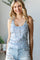 woman wearing a light blue floral tank top with button details and distressed denim shorts