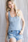 woman wearing a light blue ribbed tank top with button detail and distressed denim shorts