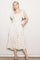 woman wearing a cream floral midi dress with ruffled sleeves and pockets, styled with nude heels