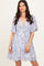 woman wearing a light blue floral print short sleeve dress with a v-neckline and a flowy skirt