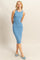 woman wearing a fitted light blue ribbed midi dress, posing with hands behind her back and wearing blue flats