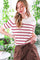 woman wearing a cream striped short sleeve top with red stripes and brown high-waisted pants