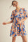 woman wearing a blue and orange floral print short sleeve dress with gathered detail and tie straps