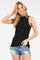 woman wearing a black sleeveless smocked top and denim shorts, smiling with one hand in her hair