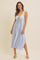woman wearing a light blue slip dress with lace details and a tie at the front, styled with white heels