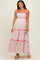 woman wearing a white maxi maternity dress with a colorful geometric pattern and red trim, featuring spaghetti straps