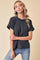woman wearing a black and white striped short sleeve top with rolled sleeves and a relaxed fit, paired with blue jeans