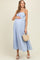 woman wearing a light blue striped maternity dress with a baby bump and holding a small woven bag