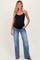 woman wearing a black maternity tank top and blue flared jeans with a visible baby bump