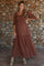woman wearing a brown maternity maxi dress with puff sleeves and floral embroidery, showing her baby bump