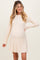 woman wearing a cream ribbed maternity sweater dress with long sleeves and a flowing skirt, showing her baby bump