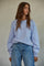 woman wearing a light lavender oversized sweater and high-waisted blue jeans