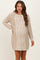 woman wearing a beige cable-knit maternity sweater dress with long sleeves and a relaxed fit, showcasing her baby bump